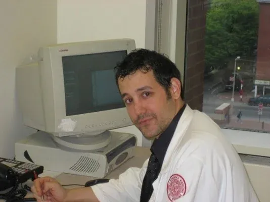 Ariel Weissmann in a white coat at his desk at Boston Medical Center.
